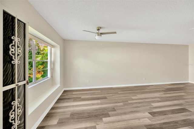 unfurnished room with ceiling fan, a textured ceiling, and light hardwood / wood-style flooring