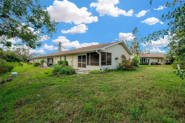 rear view of property with a lawn and a sunroom