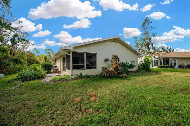 rear view of property with a lawn and a sunroom