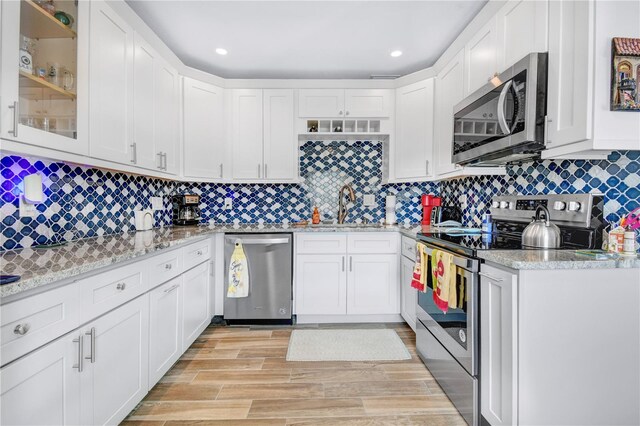 kitchen with white cabinets, sink, light stone counters, and stainless steel appliances