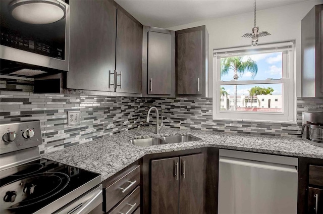 kitchen featuring backsplash, light stone counters, appliances with stainless steel finishes, and sink