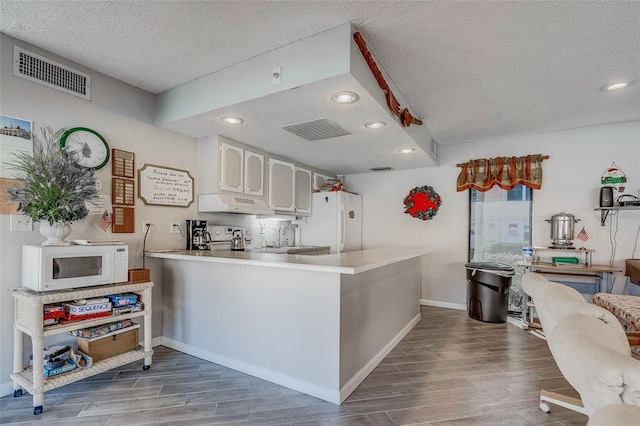 kitchen with kitchen peninsula, white appliances, a textured ceiling, gray cabinets, and hardwood / wood-style flooring