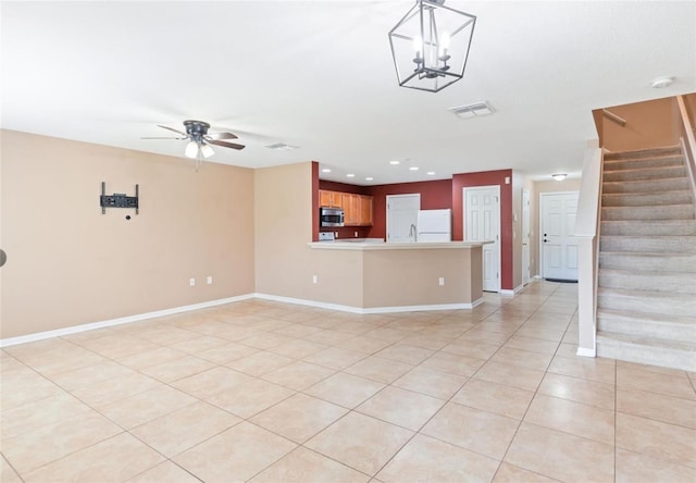 unfurnished living room featuring light tile floors, ceiling fan with notable chandelier, and sink