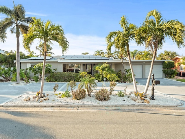 ranch-style house featuring solar panels and a garage