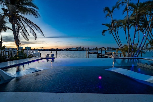 pool at dusk with a dock and a water view