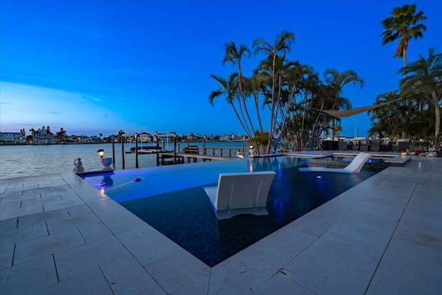 pool at dusk with a patio and a water view