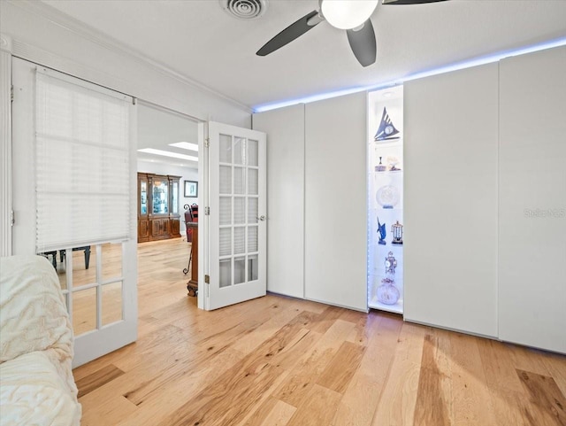 interior space featuring french doors, light wood-type flooring, crown molding, and ceiling fan