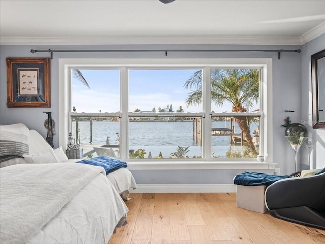 bedroom featuring light hardwood / wood-style floors, ornamental molding, and a water view