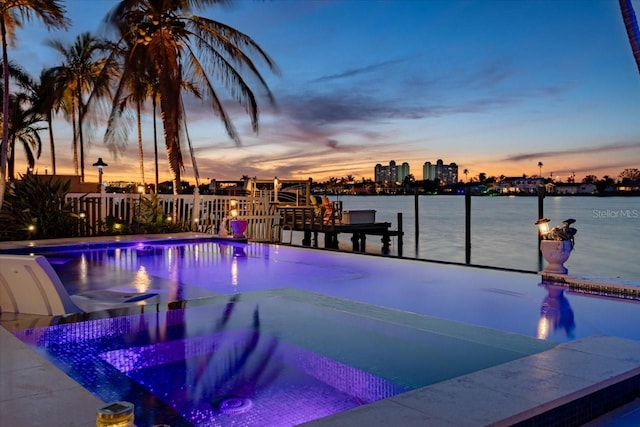 pool at dusk featuring a water view