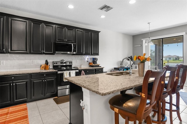 kitchen featuring a sink, visible vents, stainless steel appliances, and dark cabinets