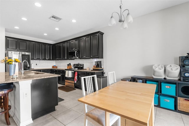 kitchen with backsplash, visible vents, stainless steel appliances, and a sink