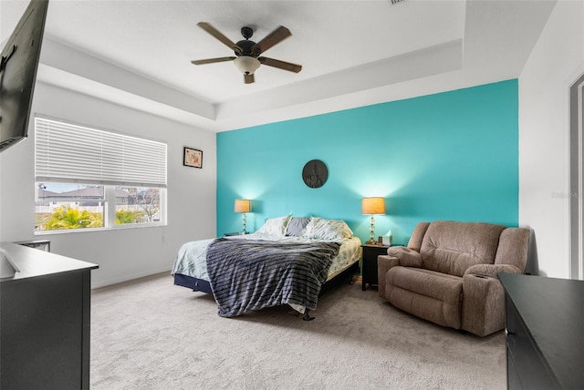 bedroom with a raised ceiling, carpet flooring, ceiling fan, and baseboards