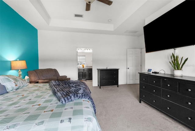 bedroom featuring light carpet, visible vents, a towering ceiling, ceiling fan, and a tray ceiling