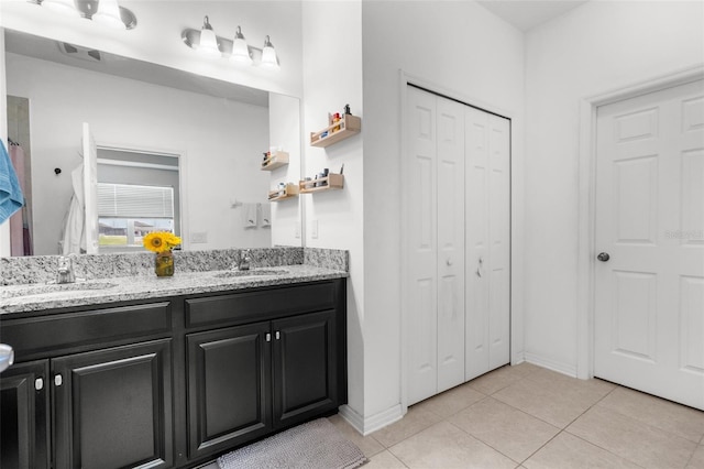 full bath with a closet, double vanity, a sink, and tile patterned floors