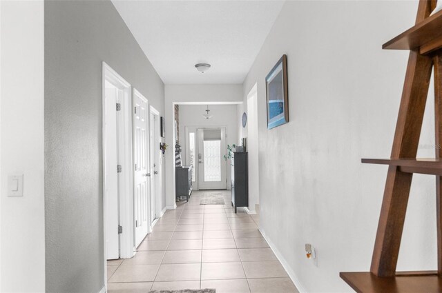 hallway featuring baseboards and light tile patterned flooring