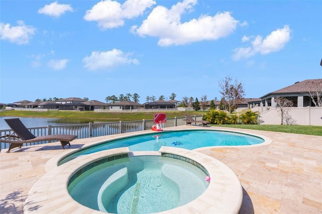 view of pool featuring a patio area, fence, a pool with connected hot tub, and a water view