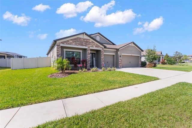 view of front facade with driveway, stone siding, an attached garage, fence, and a front yard