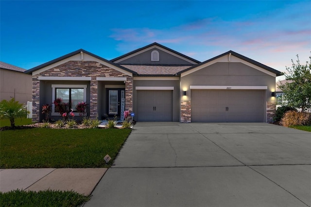 view of front facade featuring stucco siding, concrete driveway, a front yard, a garage, and stone siding