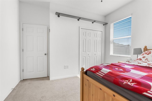 bedroom with a closet, light carpet, and baseboards