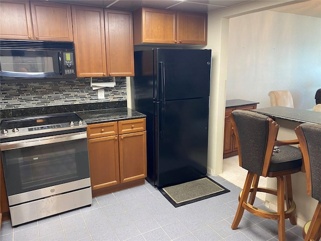 kitchen with decorative backsplash, dark stone countertops, and black appliances