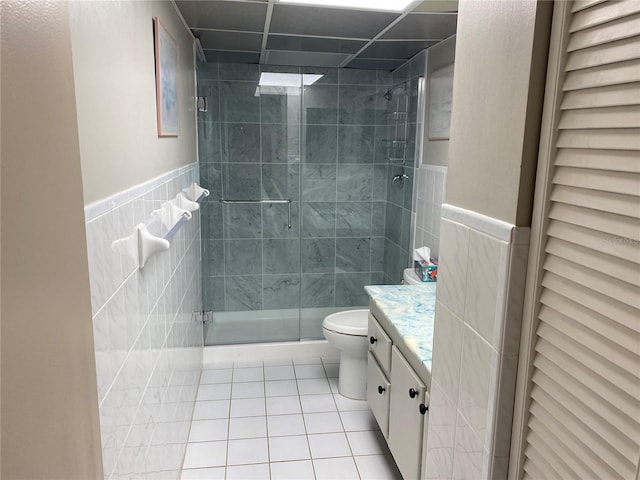 bathroom featuring tile patterned floors, vanity, toilet, and tile walls