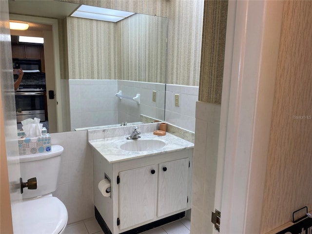 bathroom with tile patterned flooring, vanity, tile walls, and toilet