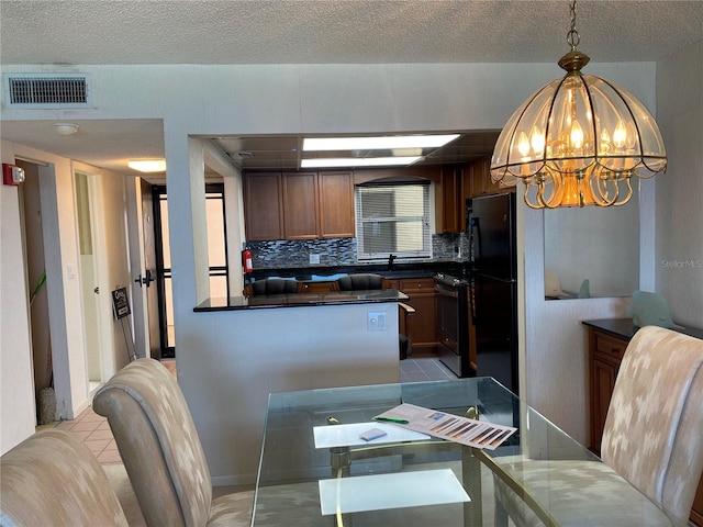 dining area featuring light tile patterned flooring, a chandelier, and a textured ceiling