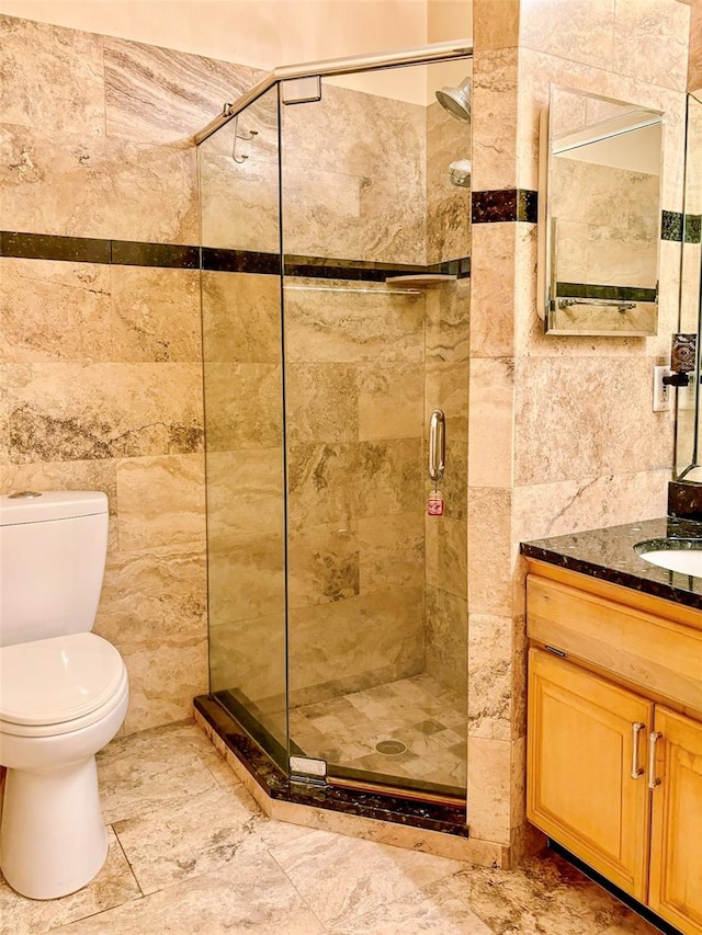 bathroom featuring vanity, tile floors, toilet, and tile walls