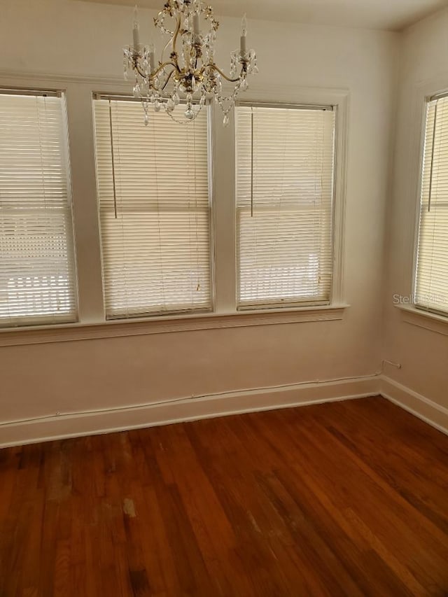 unfurnished dining area featuring a chandelier and dark hardwood / wood-style floors