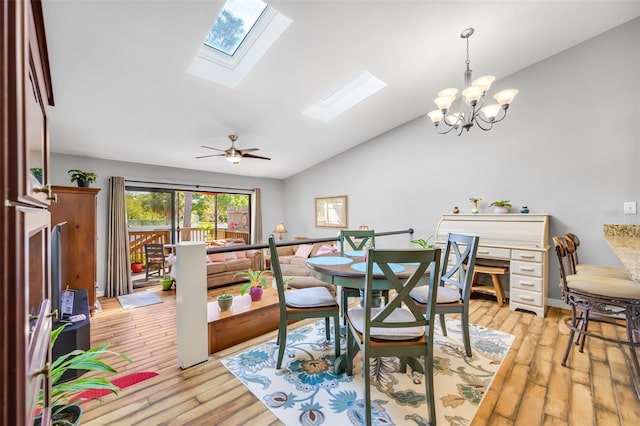 dining room featuring ceiling fan with notable chandelier, light hardwood / wood-style flooring, and vaulted ceiling with skylight