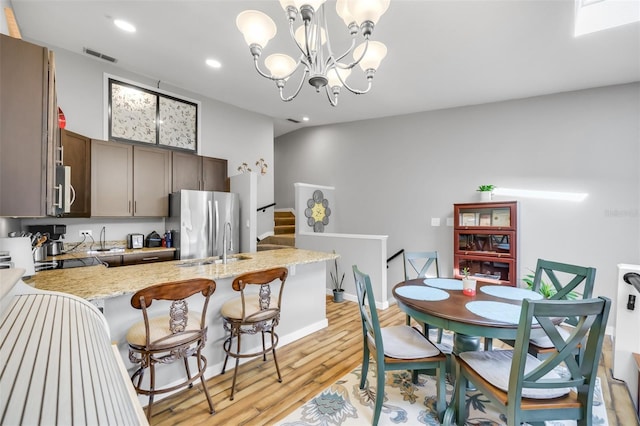 dining room with sink, a notable chandelier, and light wood-type flooring