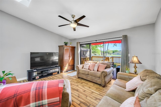 living room with light hardwood / wood-style flooring, ceiling fan, and vaulted ceiling with skylight