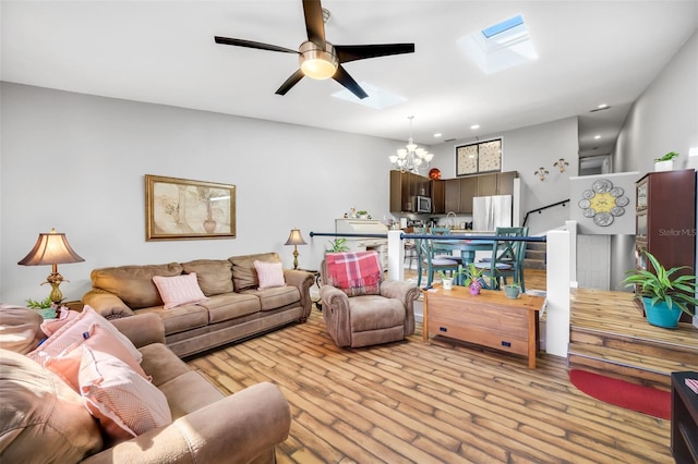 living room featuring a skylight, sink, ceiling fan with notable chandelier, and light wood-type flooring