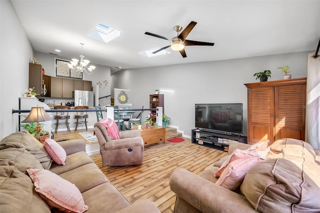 living room featuring a skylight, ceiling fan with notable chandelier, and light hardwood / wood-style floors