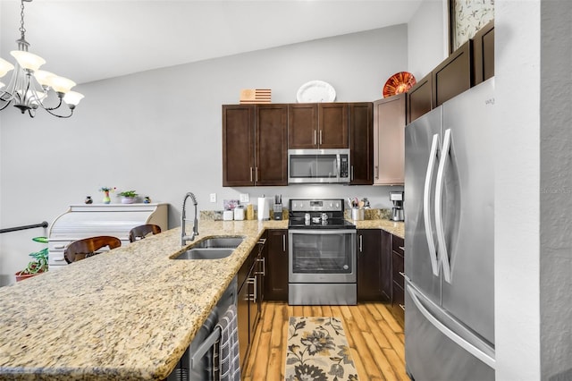 kitchen with decorative light fixtures, light wood-type flooring, an inviting chandelier, appliances with stainless steel finishes, and sink