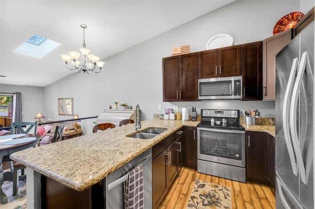 kitchen with hanging light fixtures, light hardwood / wood-style flooring, stainless steel appliances, sink, and a notable chandelier