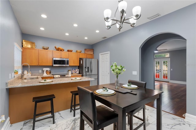 dining room with french doors, an inviting chandelier, light hardwood / wood-style flooring, and sink