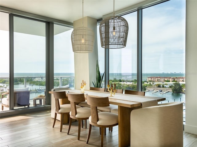 dining room featuring light hardwood / wood-style floors, expansive windows, and a water view