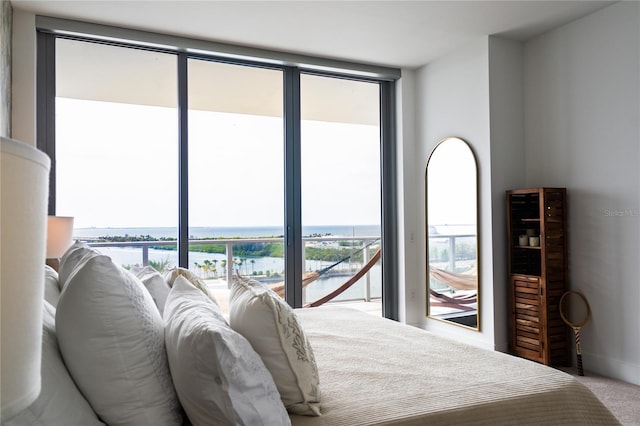 carpeted bedroom featuring floor to ceiling windows, a water view, access to exterior, and multiple windows