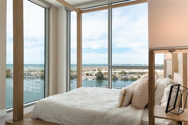 bedroom with a water view and expansive windows