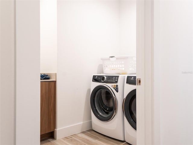 laundry area featuring washing machine and dryer and light wood-type flooring