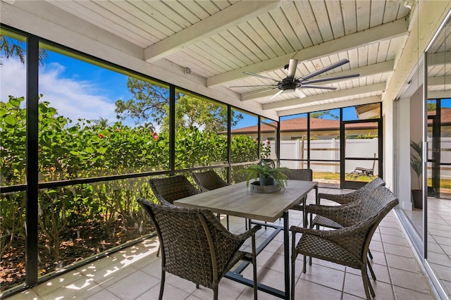 sunroom with ceiling fan and beam ceiling