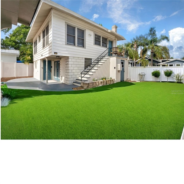 rear view of property featuring a yard and a patio area