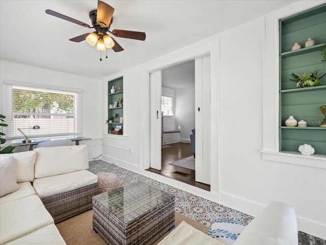 living room featuring built in shelves, ceiling fan, and wood-type flooring