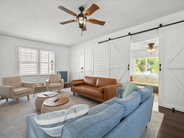 living room featuring a barn door, dark hardwood / wood-style floors, and ceiling fan