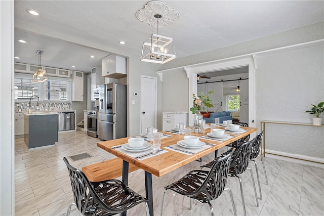 dining space featuring a barn door, light tile floors, and sink