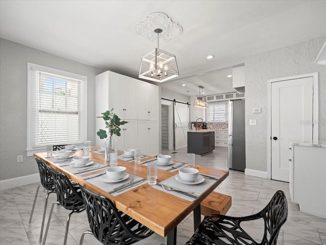 tiled dining space with a barn door, sink, and an inviting chandelier