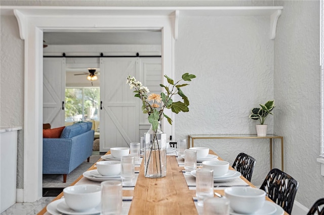 dining space with a barn door and ceiling fan