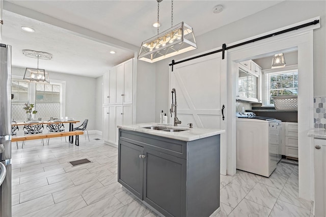 kitchen with pendant lighting, light tile floors, a barn door, gray cabinets, and sink