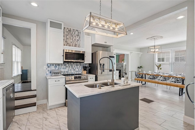 kitchen with a kitchen island with sink, hanging light fixtures, white cabinetry, and stainless steel appliances